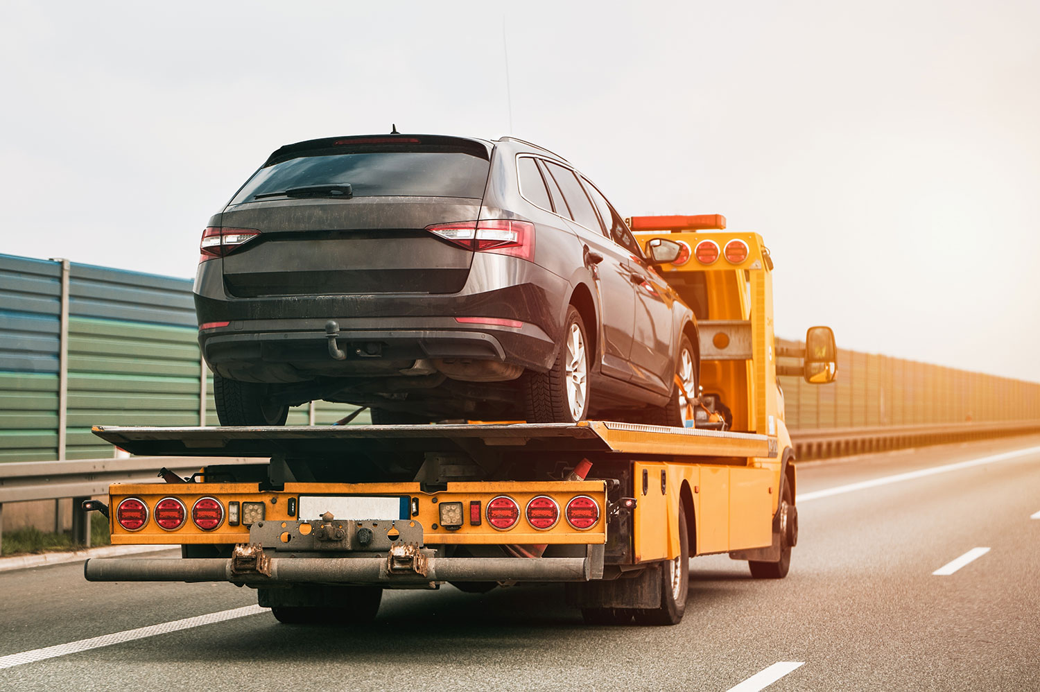 An image of a car on the back of a tow truck being driven down the road