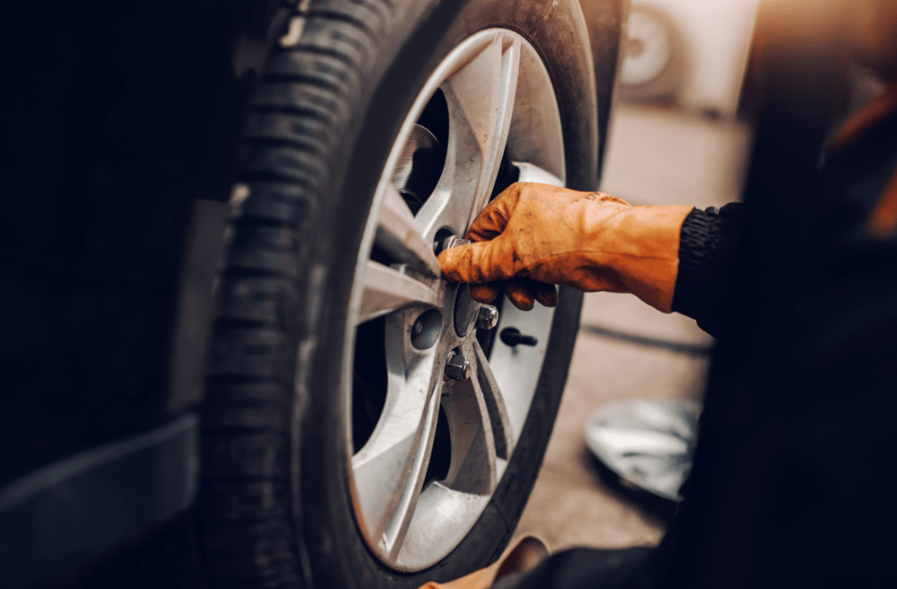 An image showing the close up of a person changing a tyre