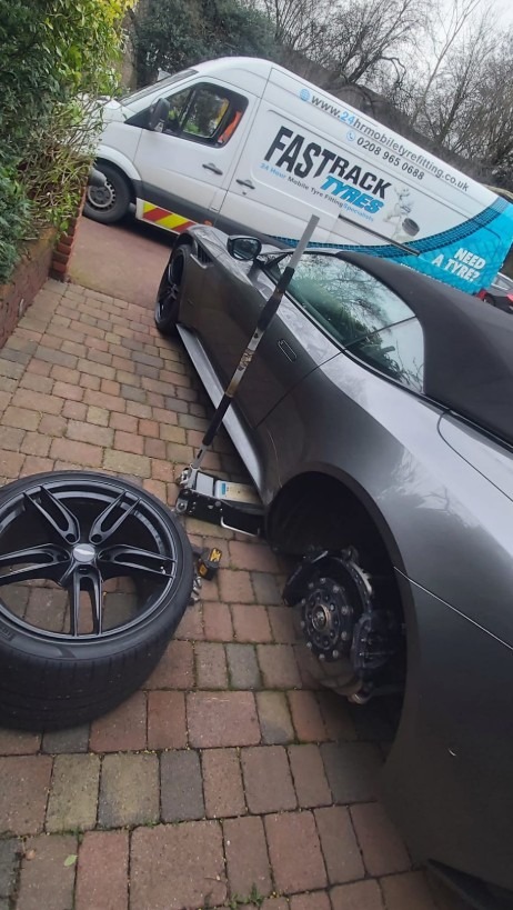 An image showing a car on a jack with its tyre removed